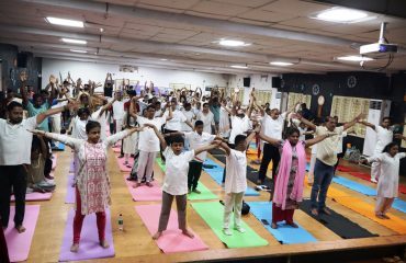अंतर्राष्ट्रीय योग दिवस के अवसर पर आयोजित योग सत्र के दौरान दिव्यांगजन, कर्मचारी और विद्यार्थी योग करते हुए।