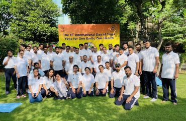 Group photograph of RCI officials during the 11th International Day of Yoga celebration with banner 'Yoga for One Earth, One Health' in the background.