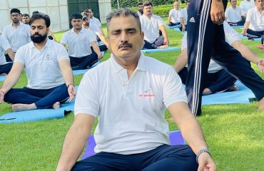 RCI officials practicing yoga in lotus position during Yoga Day celebration in an outdoor garden.