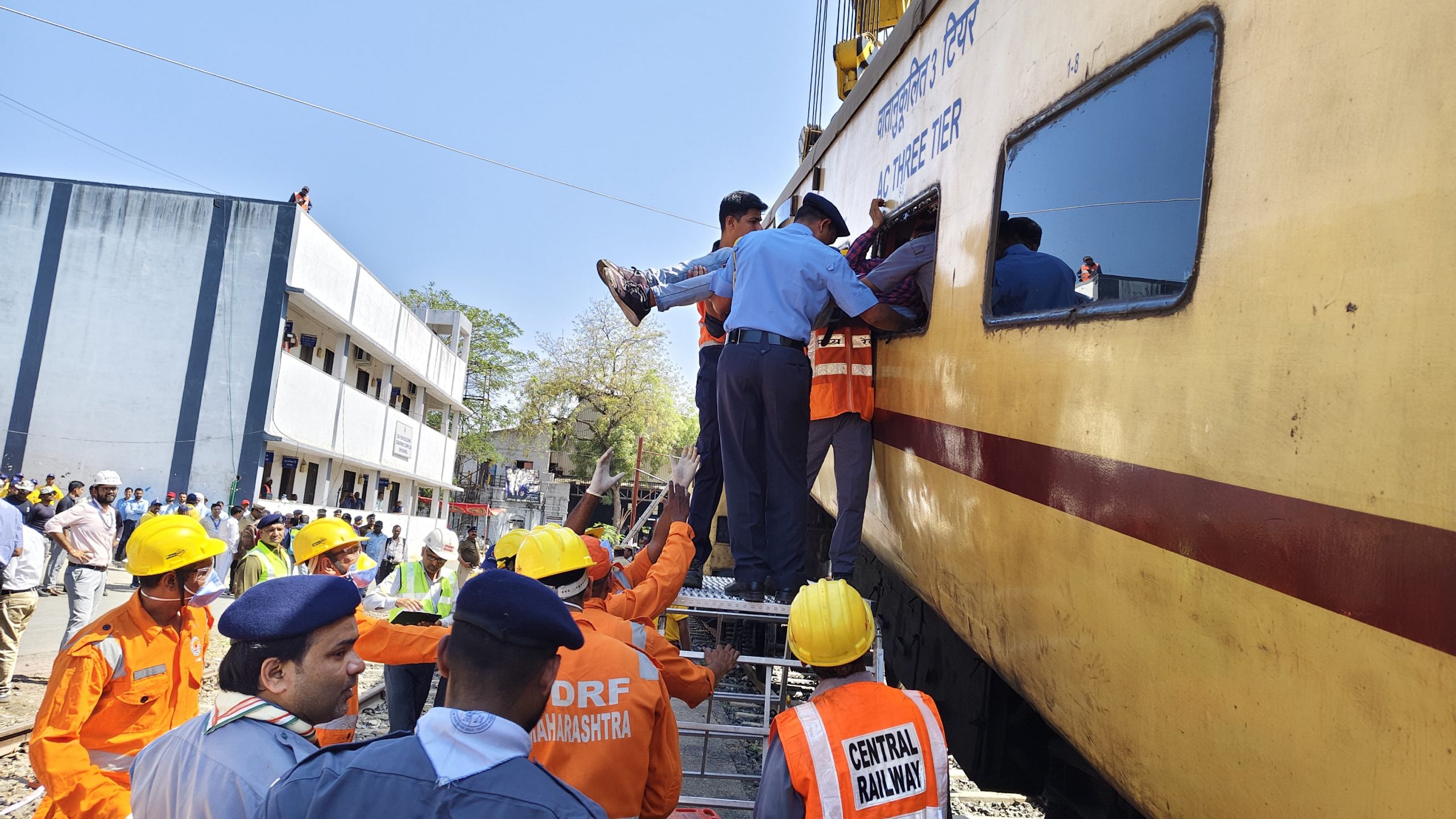 Emergency response drill: NDRF staff assisting a victim through the emergency window of a stationary train
