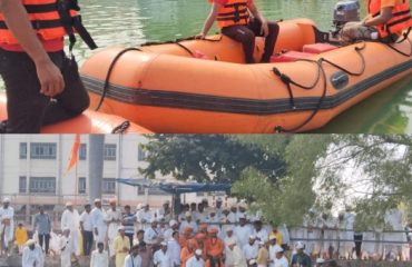 सोलापूरातील यात्रा  सणादरम्यान घाटावर पांढऱ्या पोशाखातील भाविकांचा मोठा जमाव जमला असताना सिद्धेश्वर तलावावर बचाव नौकेसह नारिंगी जीवरक्षक जॅकेट घातलेले आपदा मित्र उभे असताना