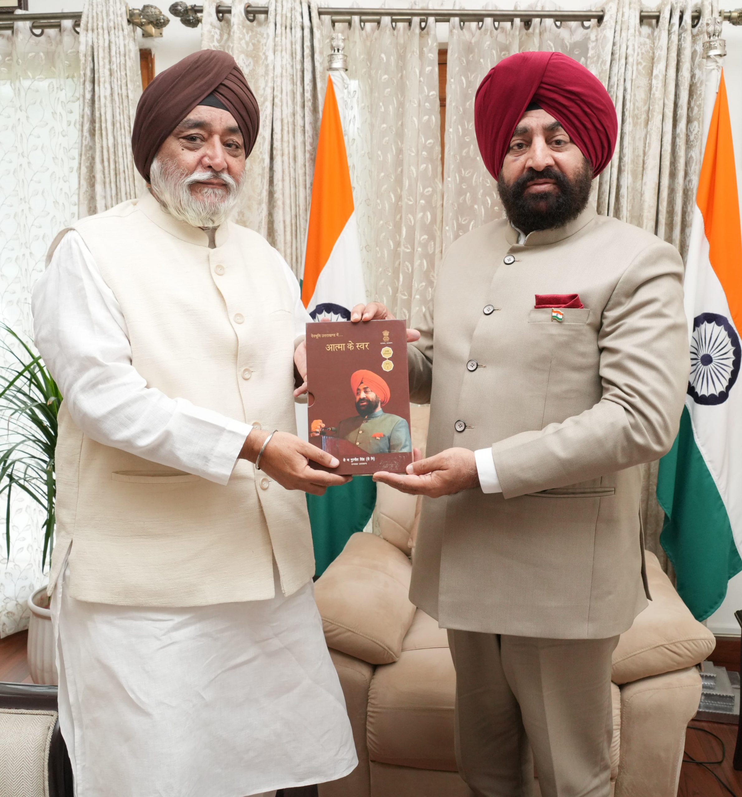Governor presenting the book 'Atma ke Swar' to Chairman of Hemkund Sahib Management Trust, Narendrajit Singh Bindra.