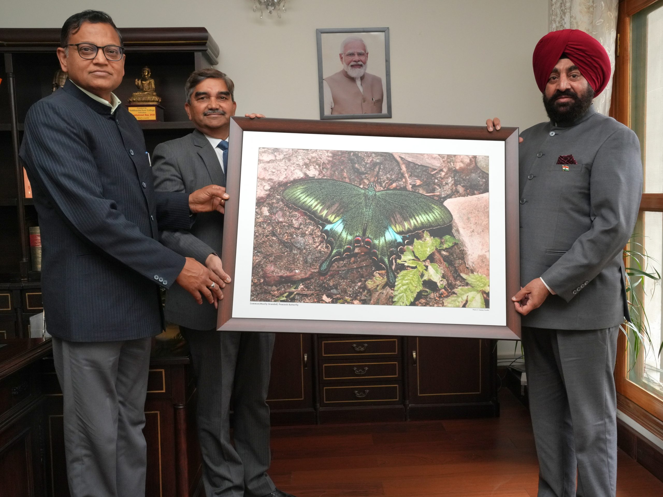 Forest department officials presenting a butterfly photo frame to the Governor.