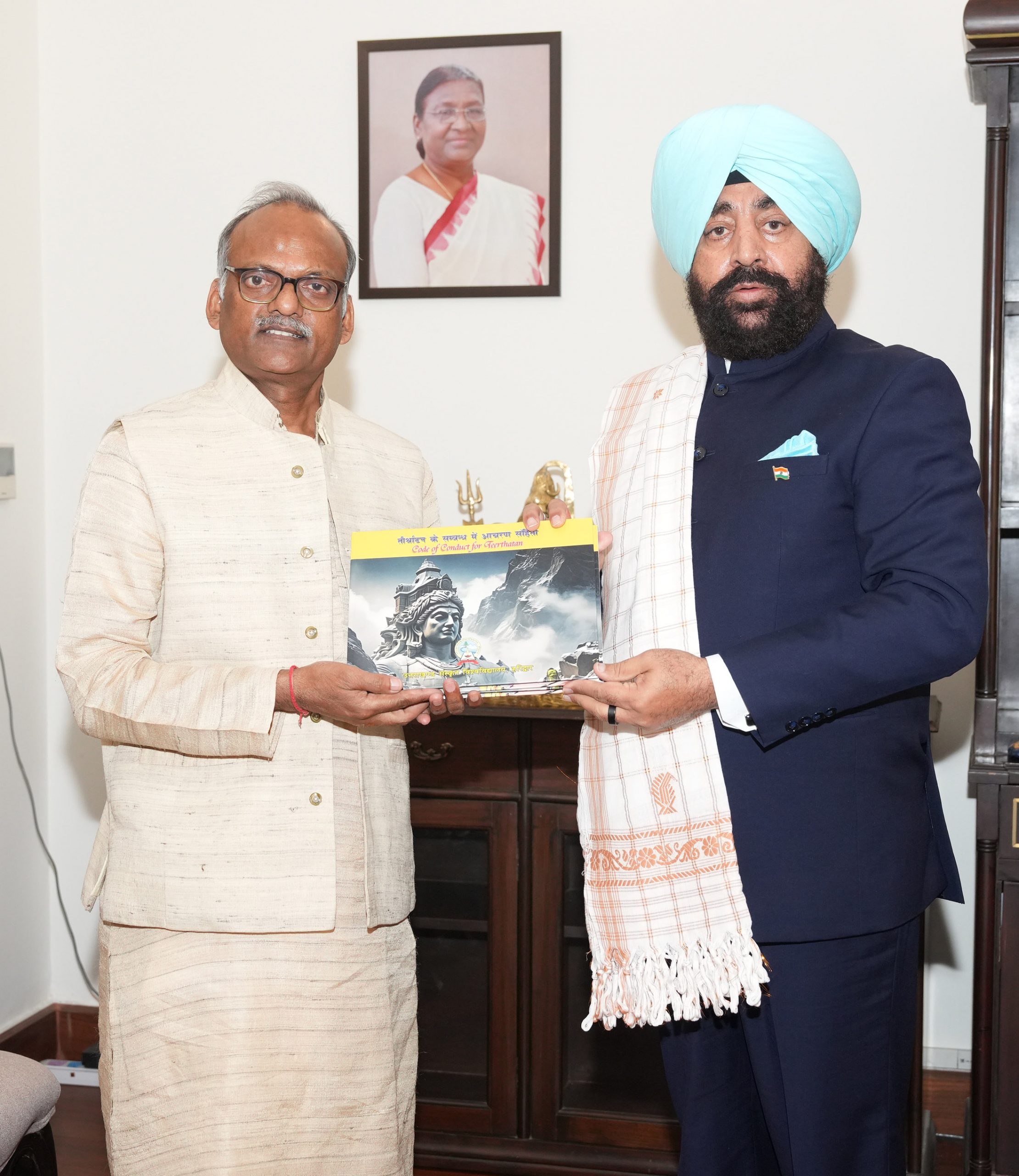 Vice Chancellor of Uttarakhand Sanskrit University Prof. Dinesh Chandra Shastri presenting the book of research work done under 'One University-One Research' to the Governor.