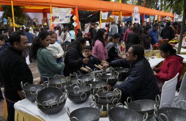 स्टॉलों में लगे उत्पादों की जानकारी प्राप्त कर खरीदारी करते हुए लोग।