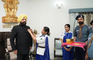 ⁠Delegation of Bharat Scouts and Guides putting a flag sticker on the Governor.