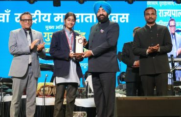 Governor felicitating a student in the program organized on the occasion of National Voters' Day.