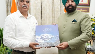 Photographer Mr. Bhumesh Bharti presenting the coffee table book 'Aerial Vistas of Uttarakhand' to the Governor.