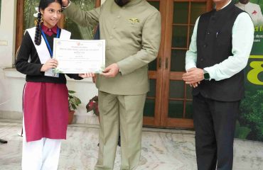 Governor honouring a student for her significant contribution in forest conservation and environmental awareness on the occasion of Harela festival.