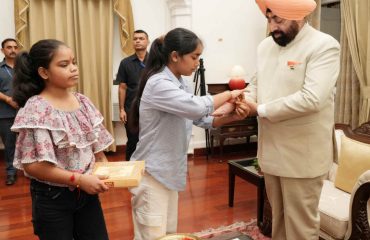 राज्यपाल को रक्षासूत्र बांधती हुईं छात्राएं।
