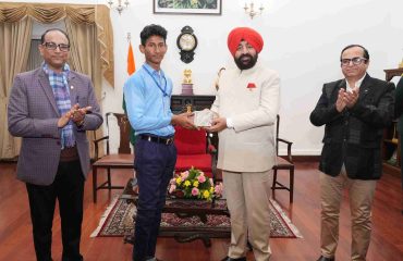 The Governor honoring a male student who returned from the Bharat Darshan educational trip at Lok Bhavan.