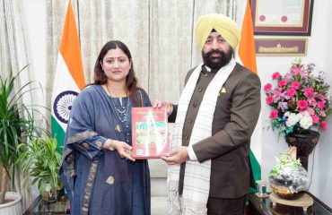 Mrs. Geeta Dhami presenting a book to the Governor.