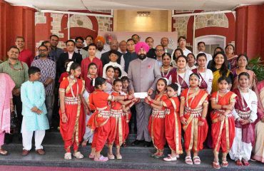 The Governor presenting cheques to young girls on the occasion of the program held at Lok Bhavan to celebrate the State Foundation Days of Rajasthan and Odisha.