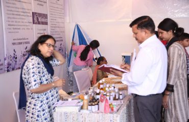 In the picture, a person is receiving information about a stall from a person with a disability.