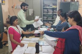 शिक्षक परीक्षा विभाग में पेपर एकत्र कर रहे हैं।